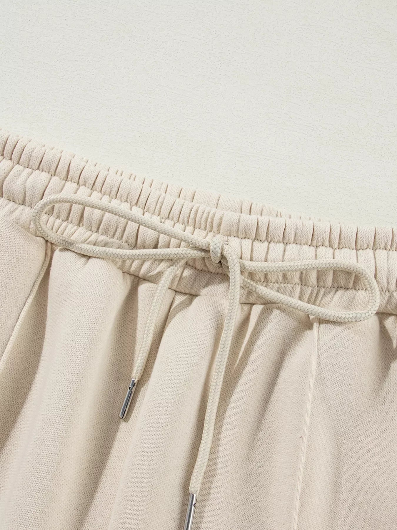 Close-up of beige sweatpants waistband with elastic and tied drawstring
