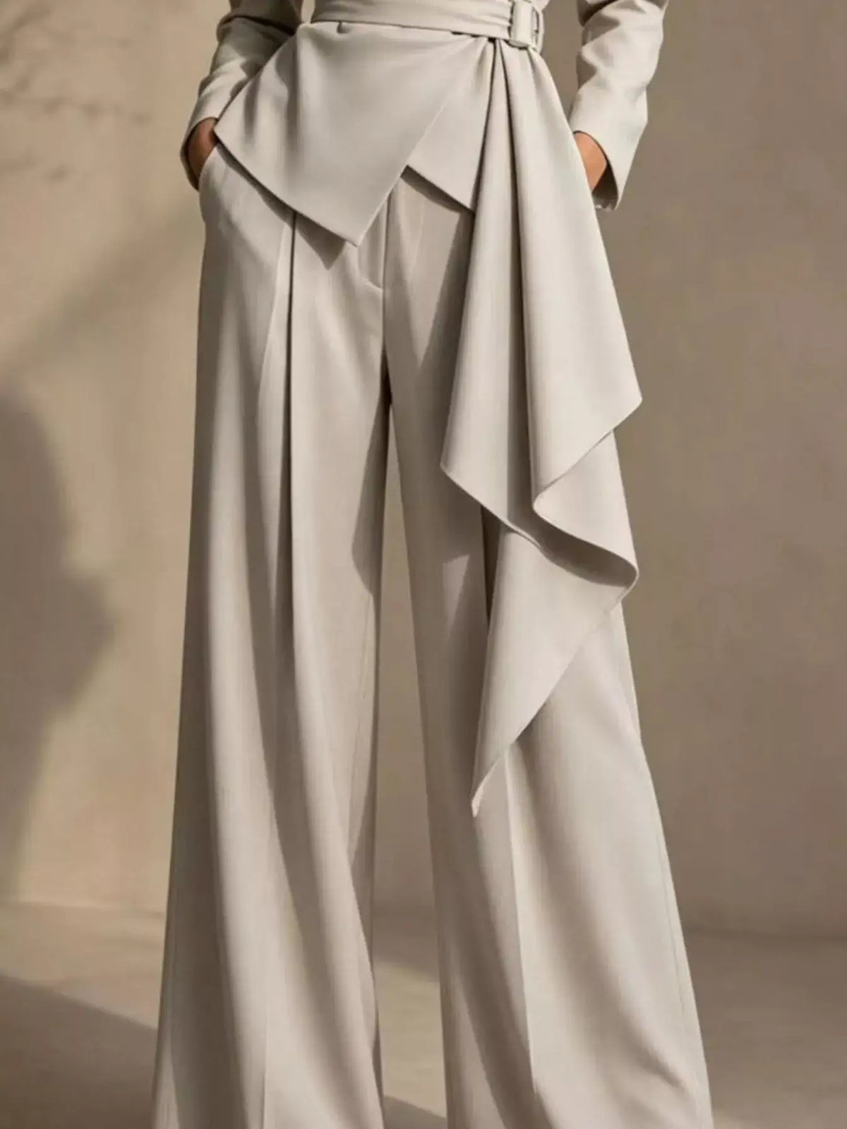 Evie's Dreamland beige belted blazer and wide-leg pants set with a dramatic draped waist detail.