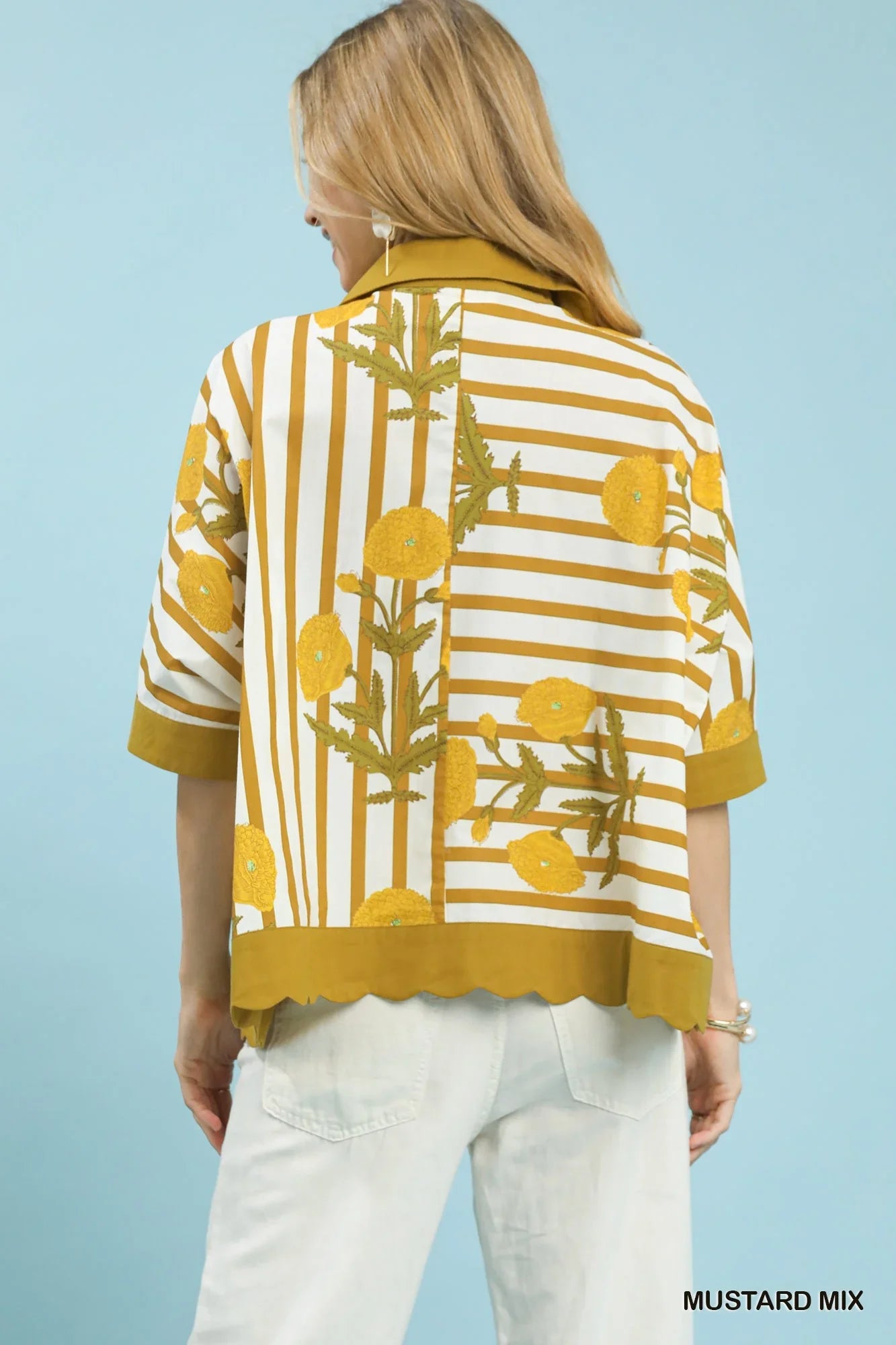 Woman in mustard yellow floral striped blouse with scalloped hem and light pants