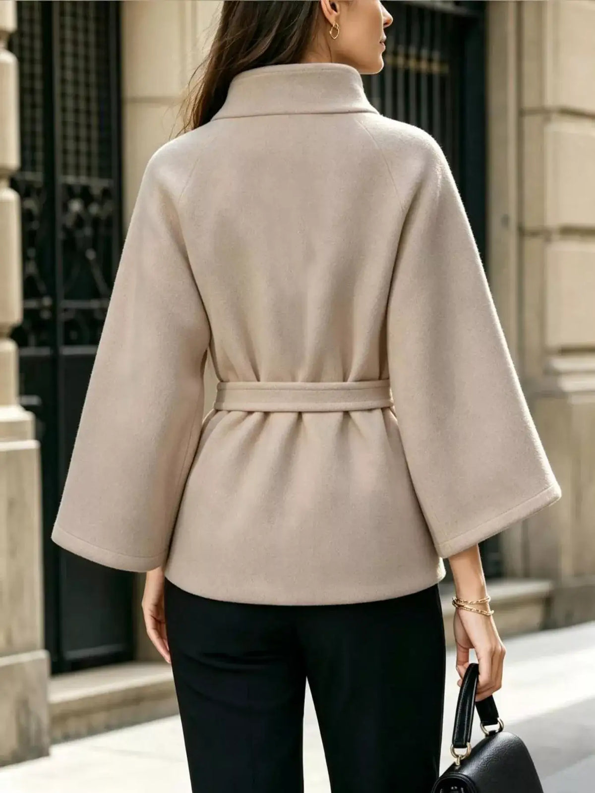 Back view of a beige Evie's Dreamland belted cape coat with wide sleeves and a high collar.