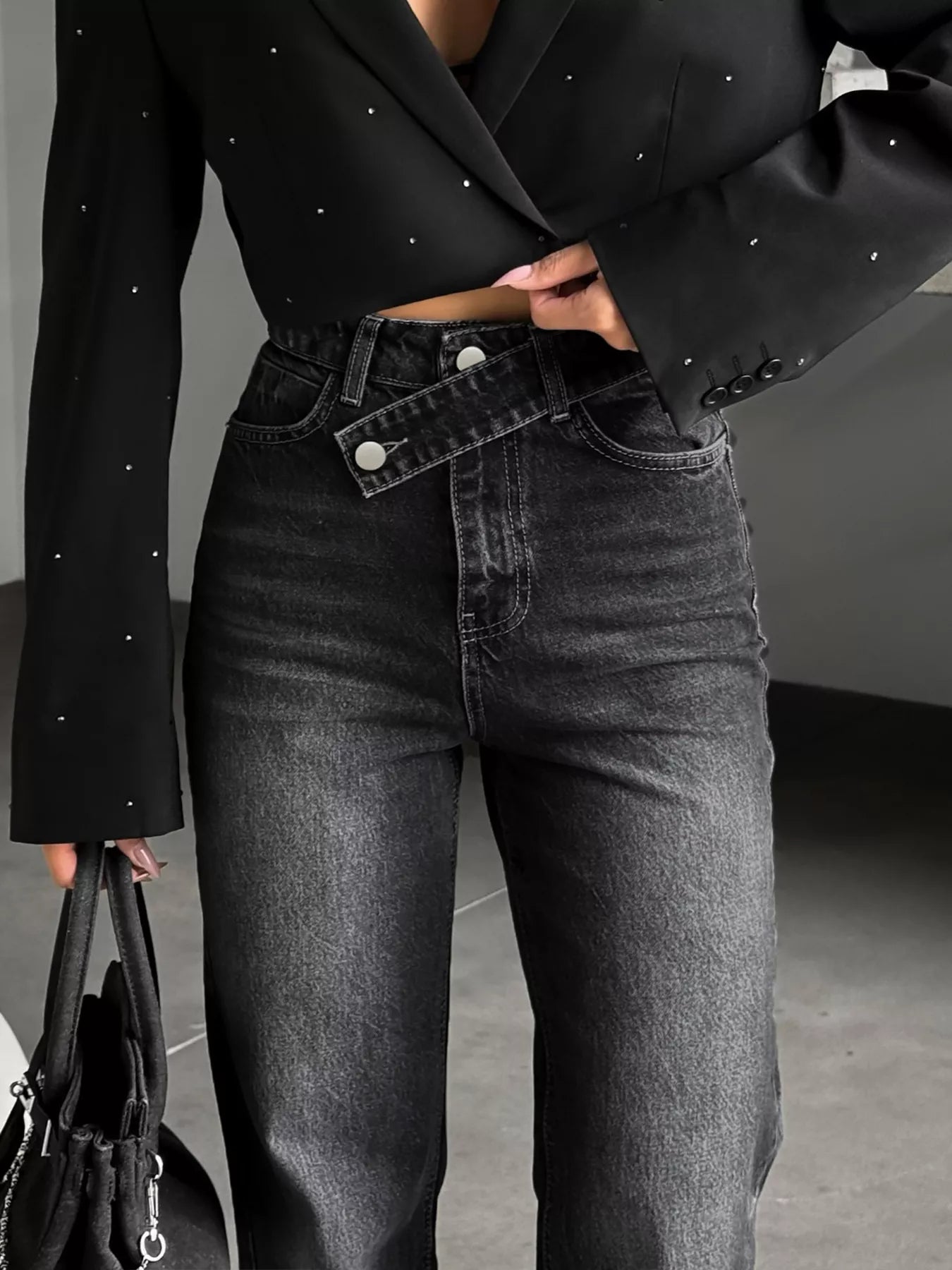 High-waisted black jeans with unique crisscross waistband, paired with a studded black blazer