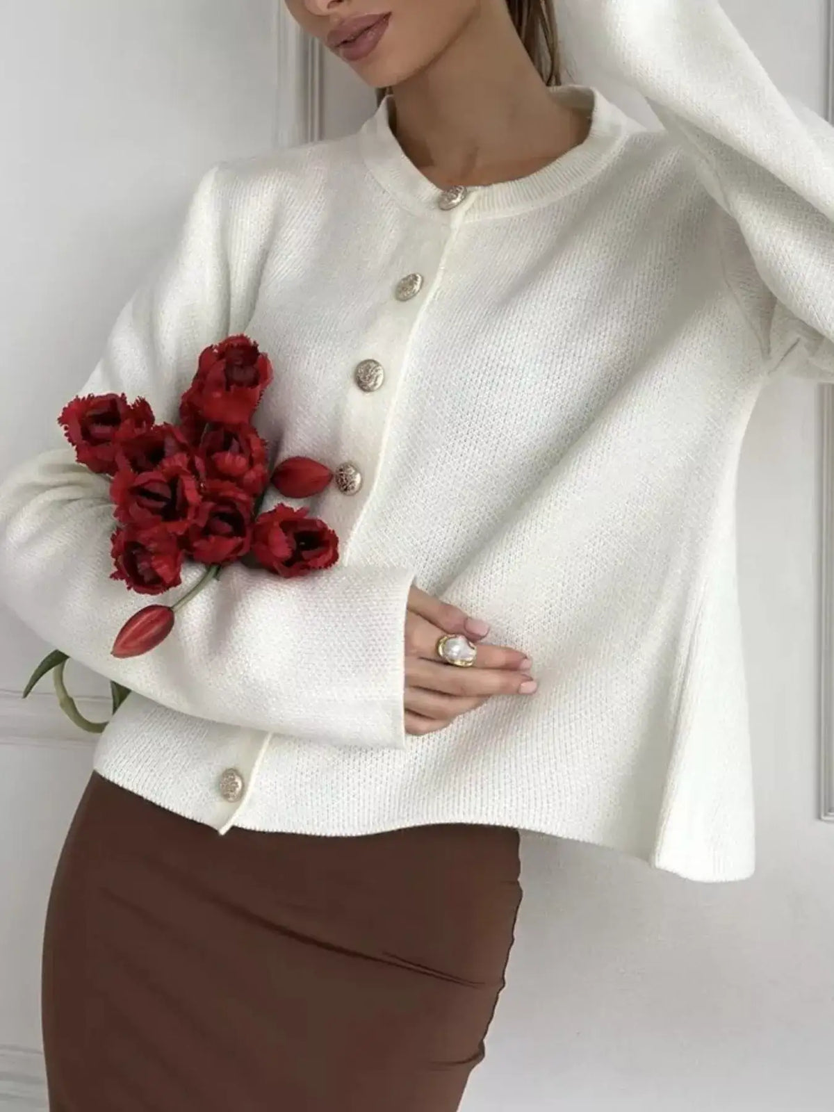 Woman wearing a white Evie's Dreamland crew neck button down cardigan with gold buttons and red tulips.