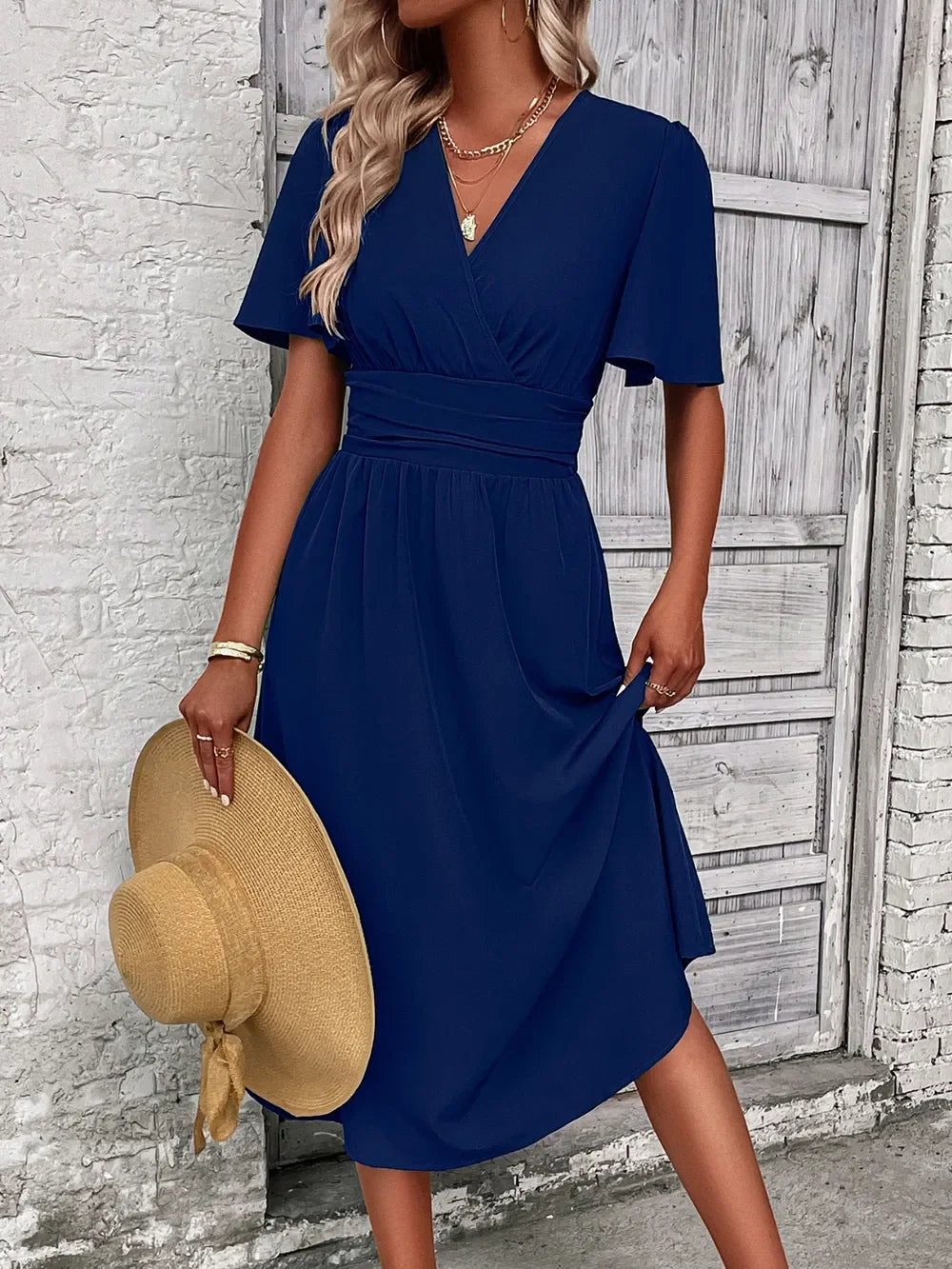 Navy blue V-neck midi dress with short sleeves, paired with straw hat and gold jewelry