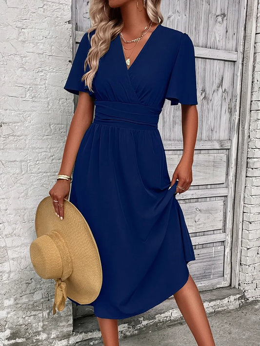 Navy blue V-neck midi dress with short sleeves, paired with straw hat and gold jewelry