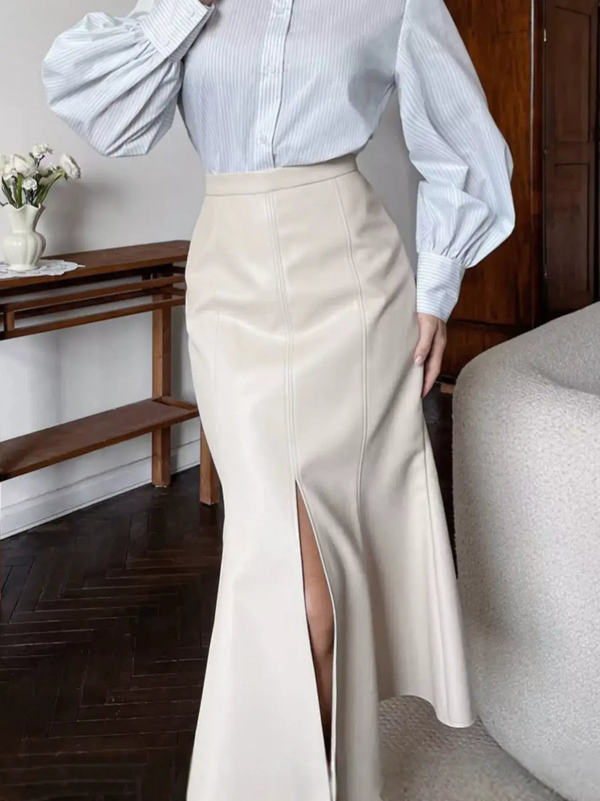 Evie's Dreamland cream faux leather mermaid midi skirt with a front slit, paired with a striped blouse.