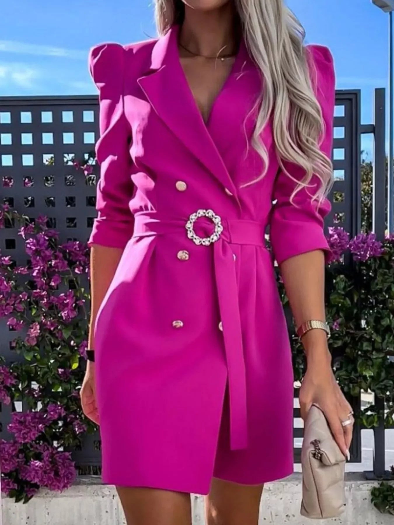 Woman wearing vibrant pink double-breasted blazer dress with padded shoulders and decorative belt