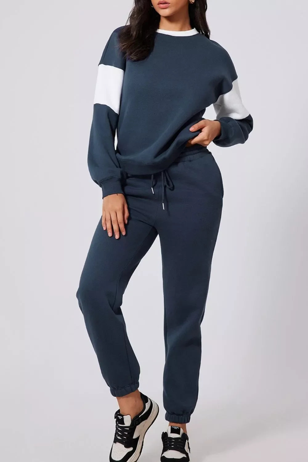 Woman wearing navy blue and white color block sweatshirt with matching jogger pants and black white sneakers