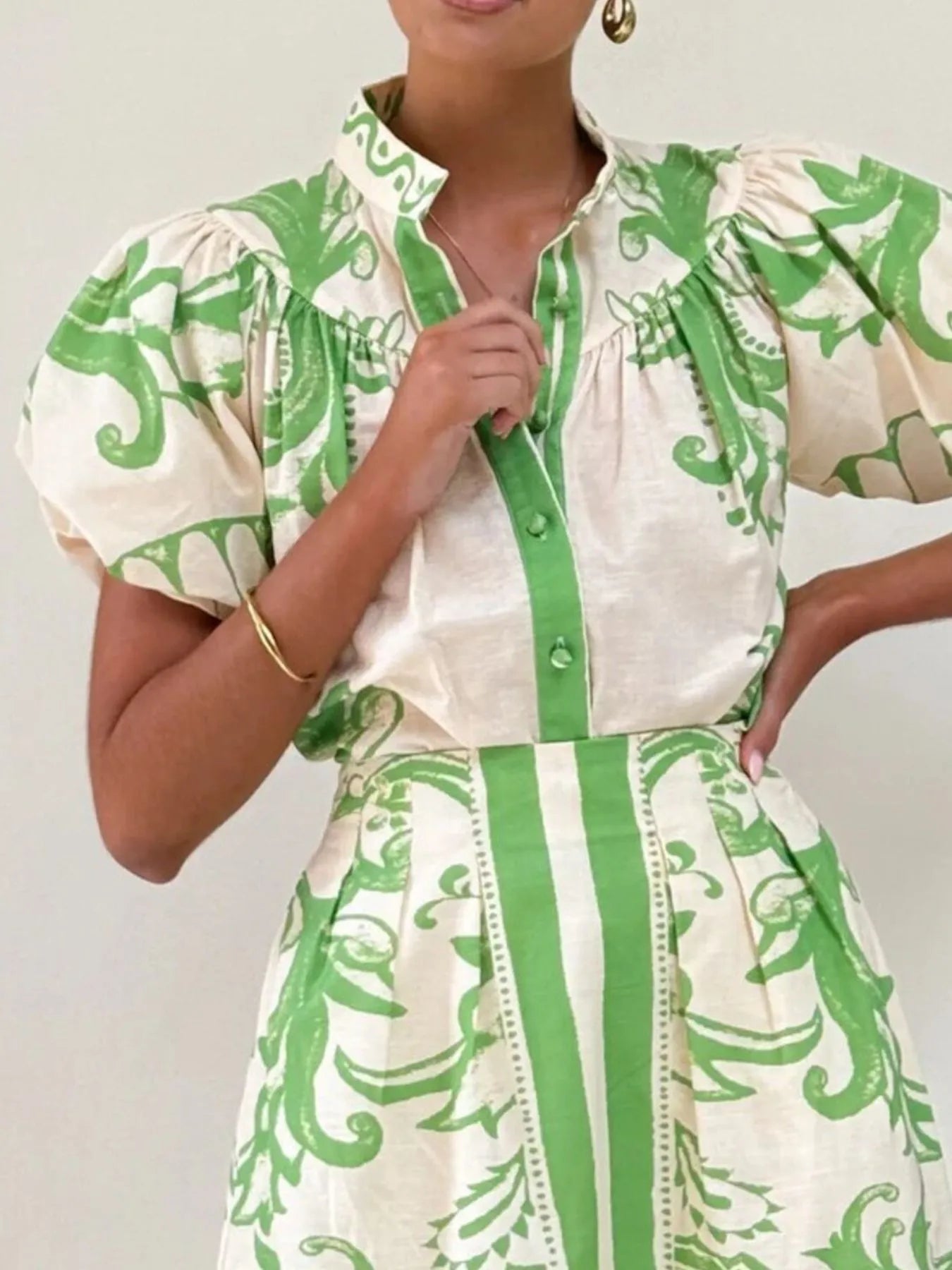 Woman wearing a puff sleeve dress with green and cream floral print and button-up front