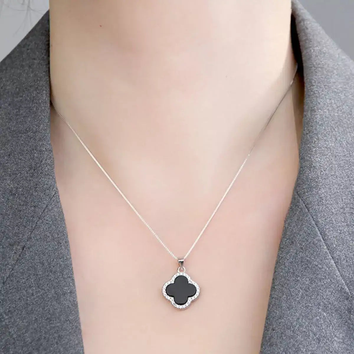 Evie's Dreamland 925 sterling silver clover pendant necklace with a black inlay on a woman's neck.