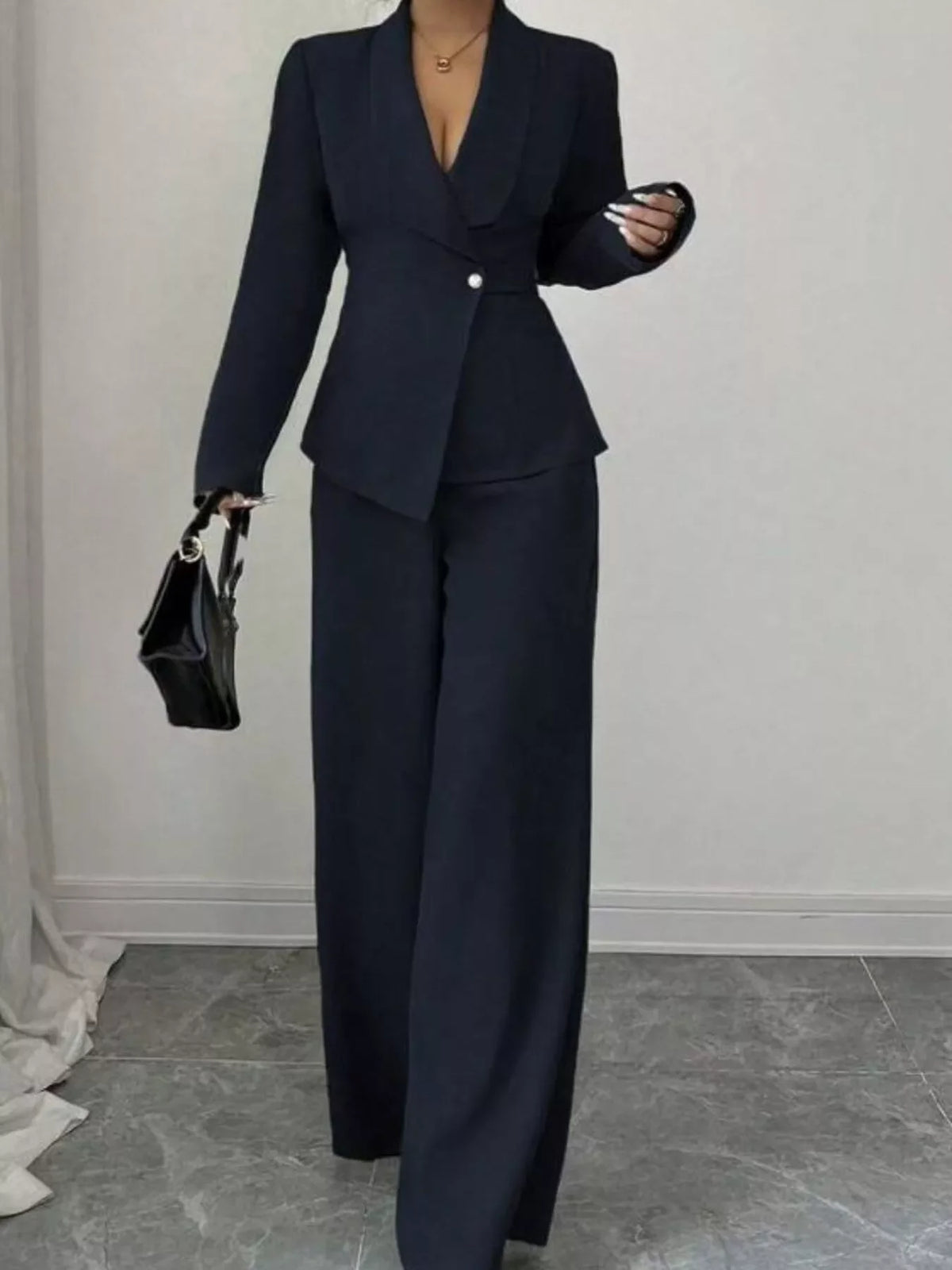 Woman wearing a chic black pantsuit with wide-leg trousers and a fitted blazer.