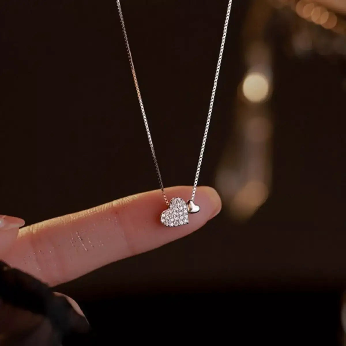 Evie's Dreamland 925 sterling silver heart necklace with zircon crystals held on a finger.