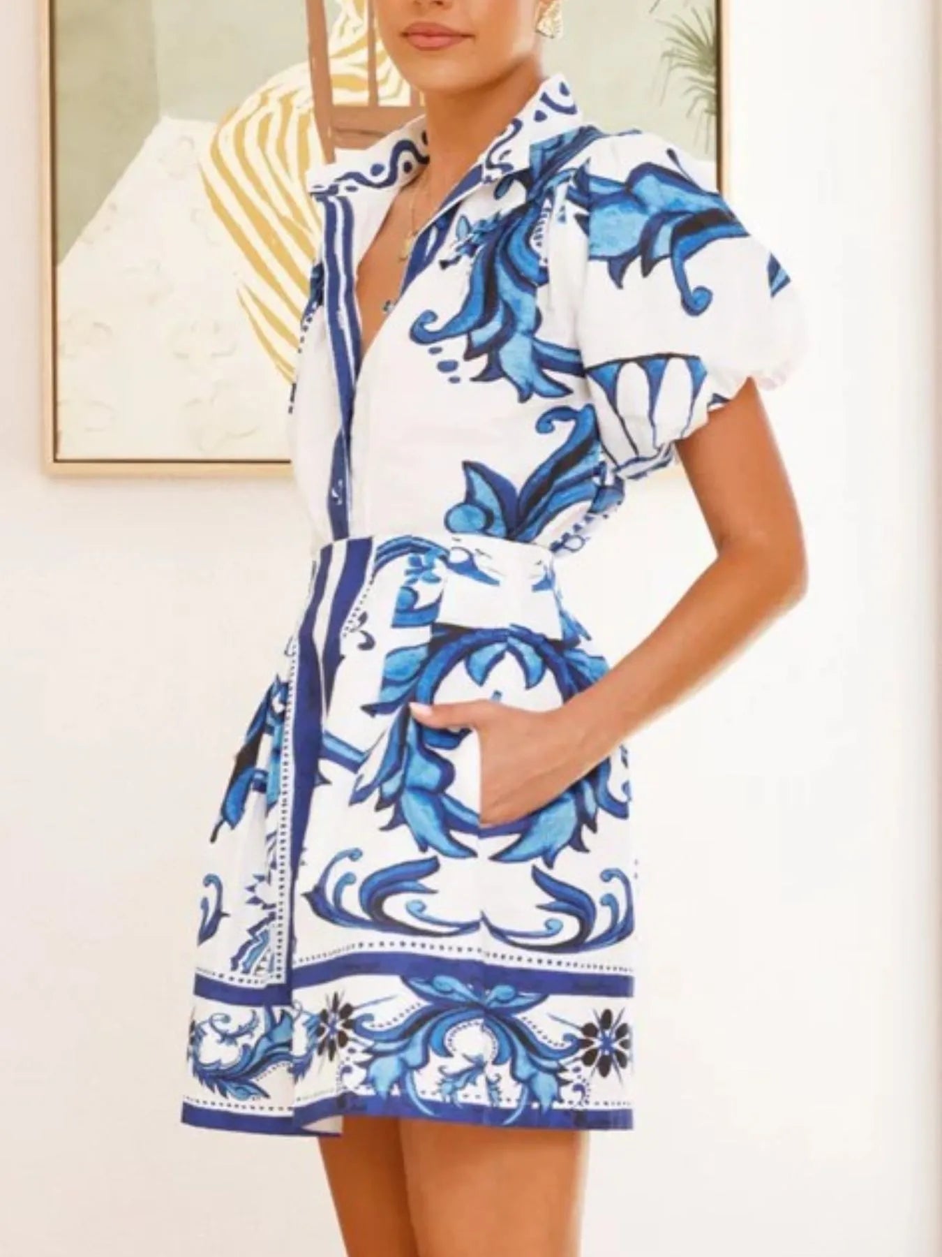 Woman wearing a short white dress with bold blue floral print and puff sleeves