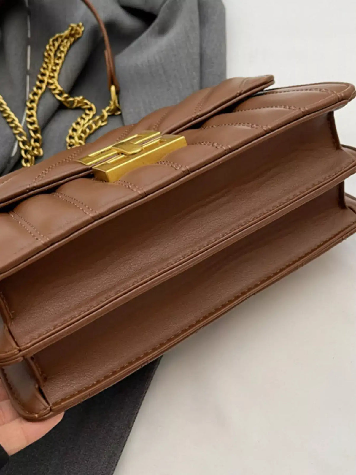 Brown quilted flap chain shoulder bag by Evie's Dreamland with a gold buckle closure.