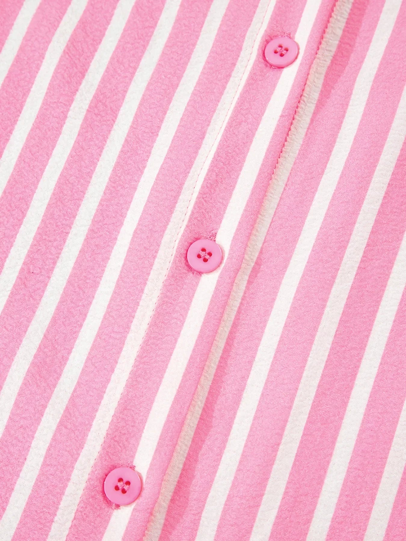 Close-up of pink and white striped fabric with pink buttons, soft textured material