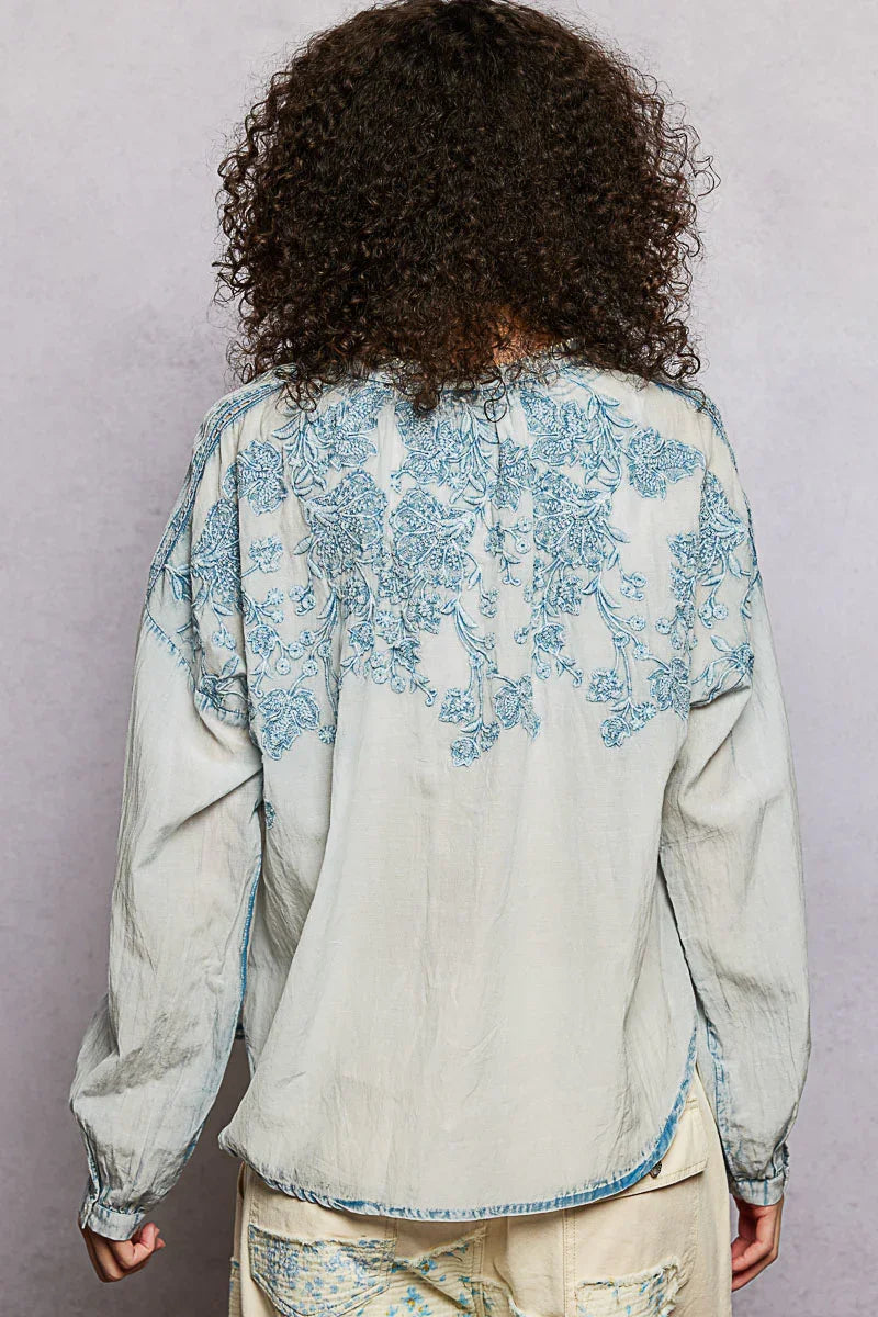 Back view of a woman in a light blue embroidered floral long sleeve blouse with relaxed fit