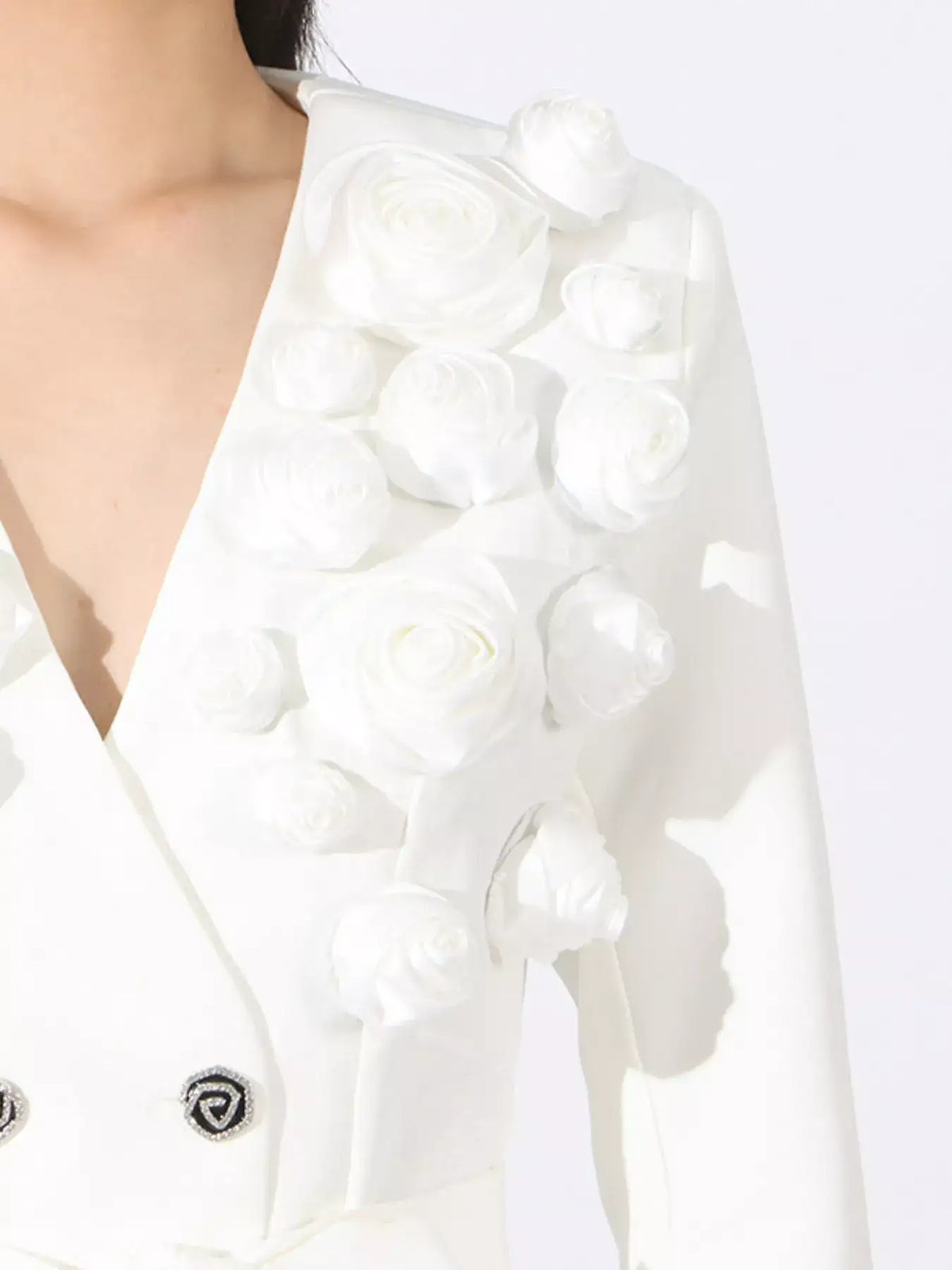 Detail of a white Evie's Dreamland double-breasted blazer featuring 3D floral fabric appliqués on the shoulder.