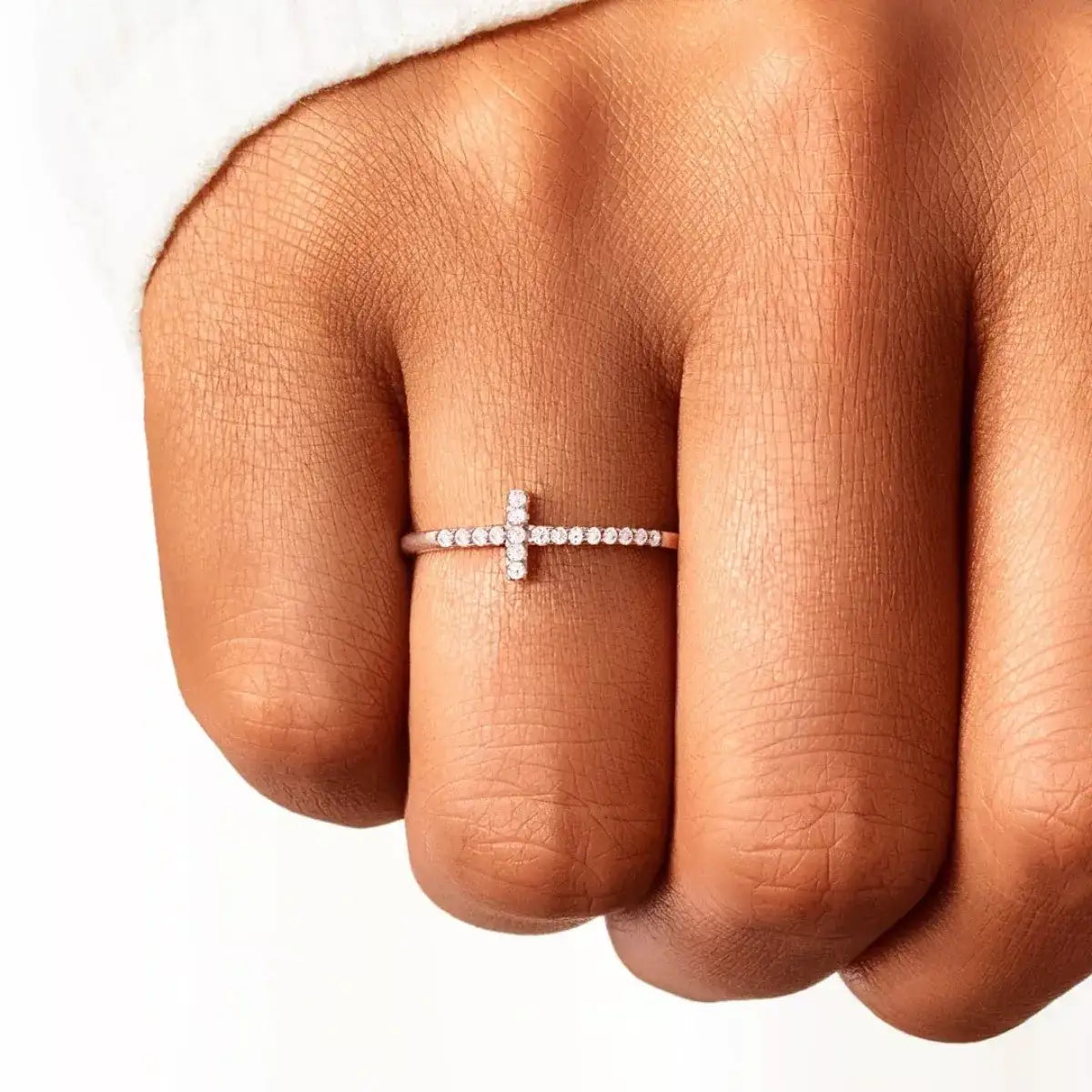 Evie's Dreamland rose gold 925 sterling silver cross ring with sparkling crystals on a woman's finger.