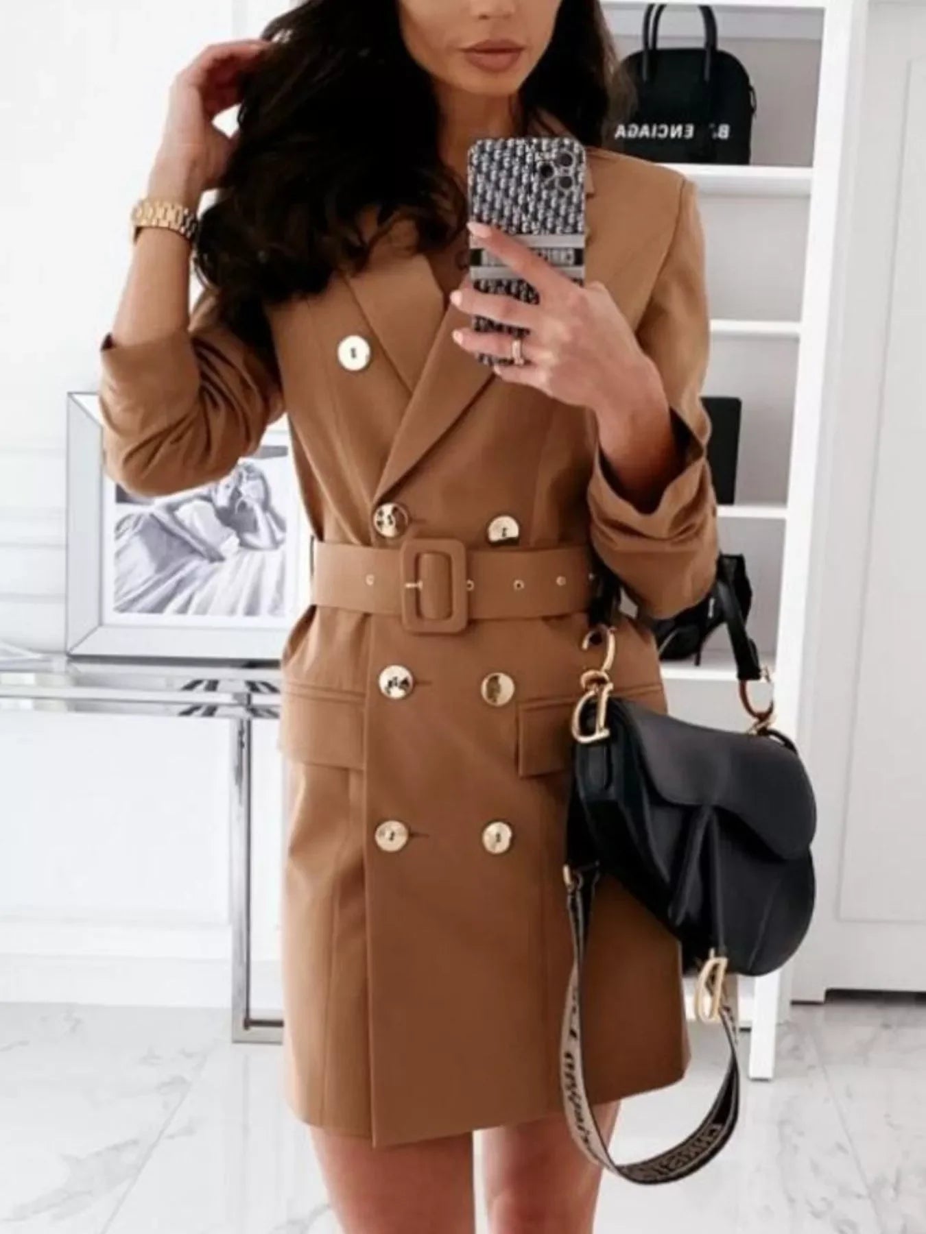 Woman wearing stylish brown belted double-breasted blazer dress with gold buttons and carrying black designer handbag
