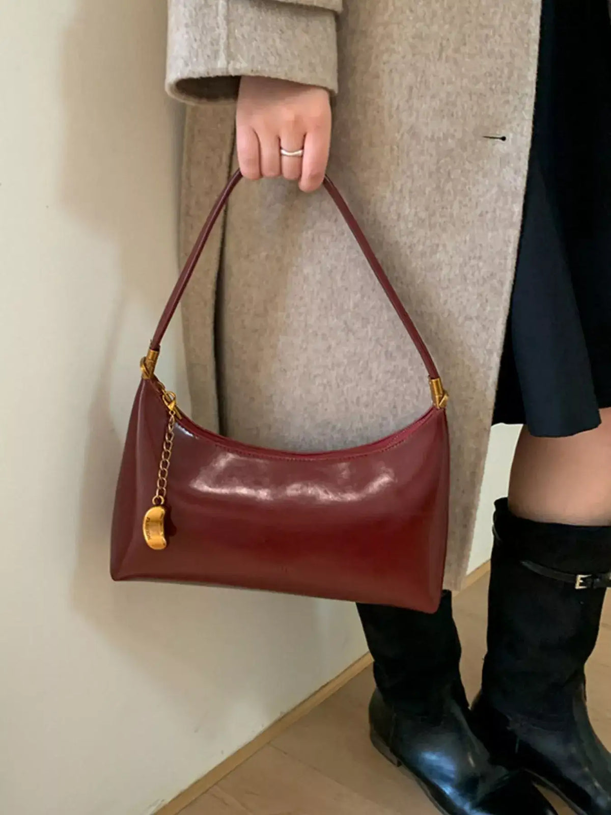 Burgundy PU leather shoulder bag by Evie's Dreamland with gold chain charm, paired with a beige coat.