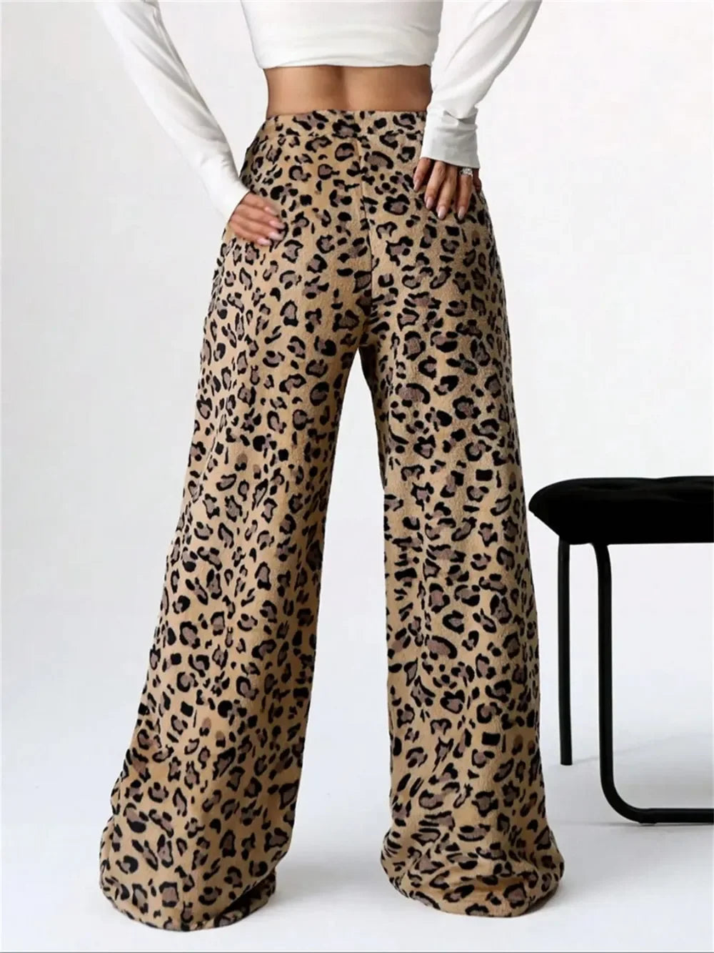 Woman wearing high-waisted wide-leg leopard print pants paired with a white long-sleeve crop top