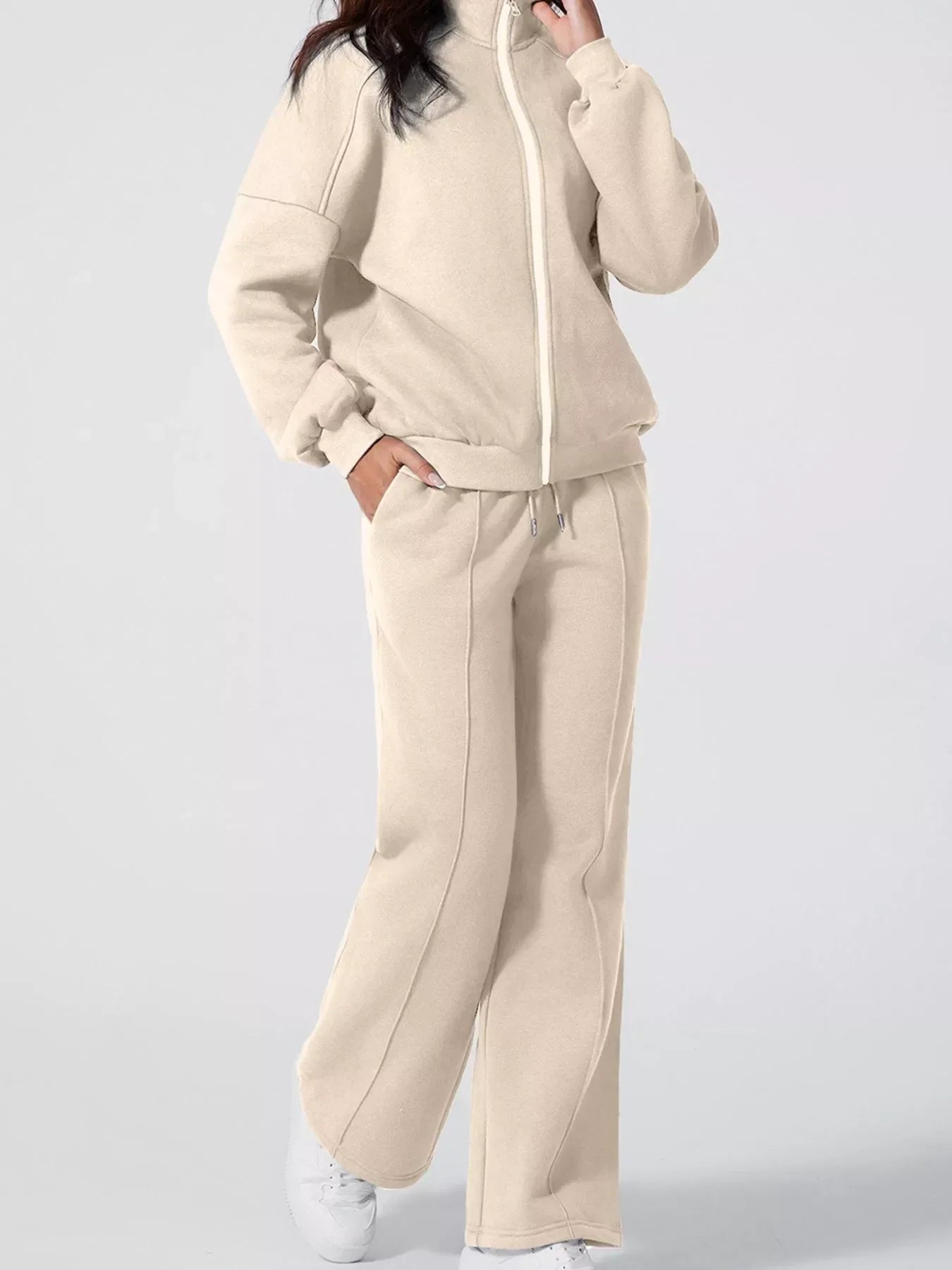 Woman wearing beige fleece zip-up jacket and matching wide-leg sweatpants with white sneakers