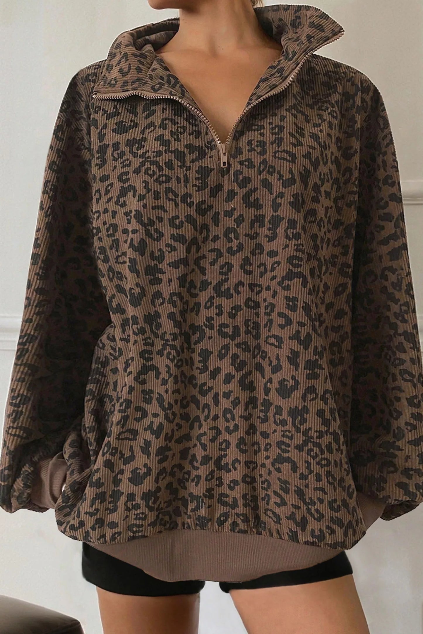 Woman wearing brown and black leopard print pullover with zip collar and balloon sleeves