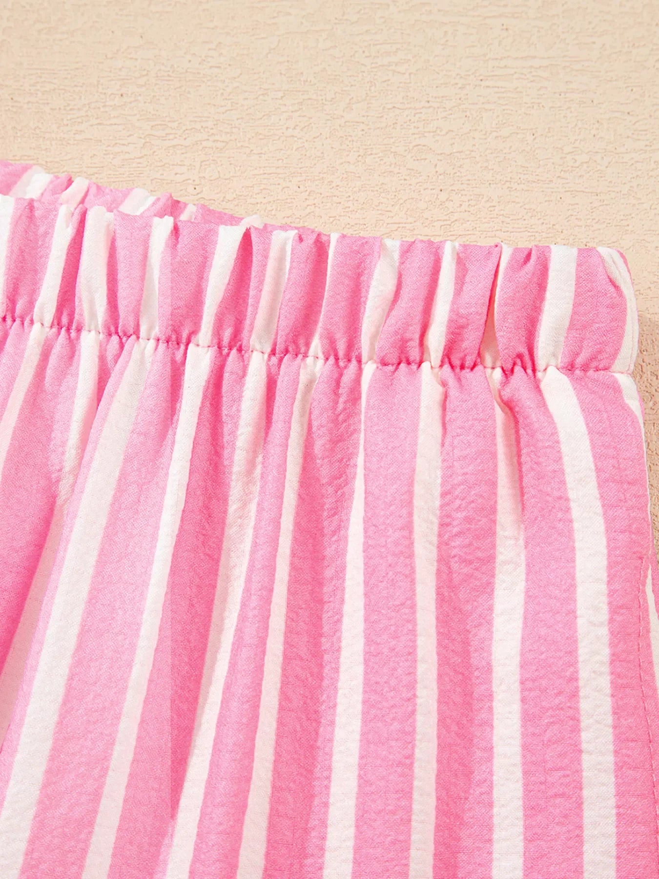 Close-up of pink and white vertical striped fabric waistband with elastic gathering