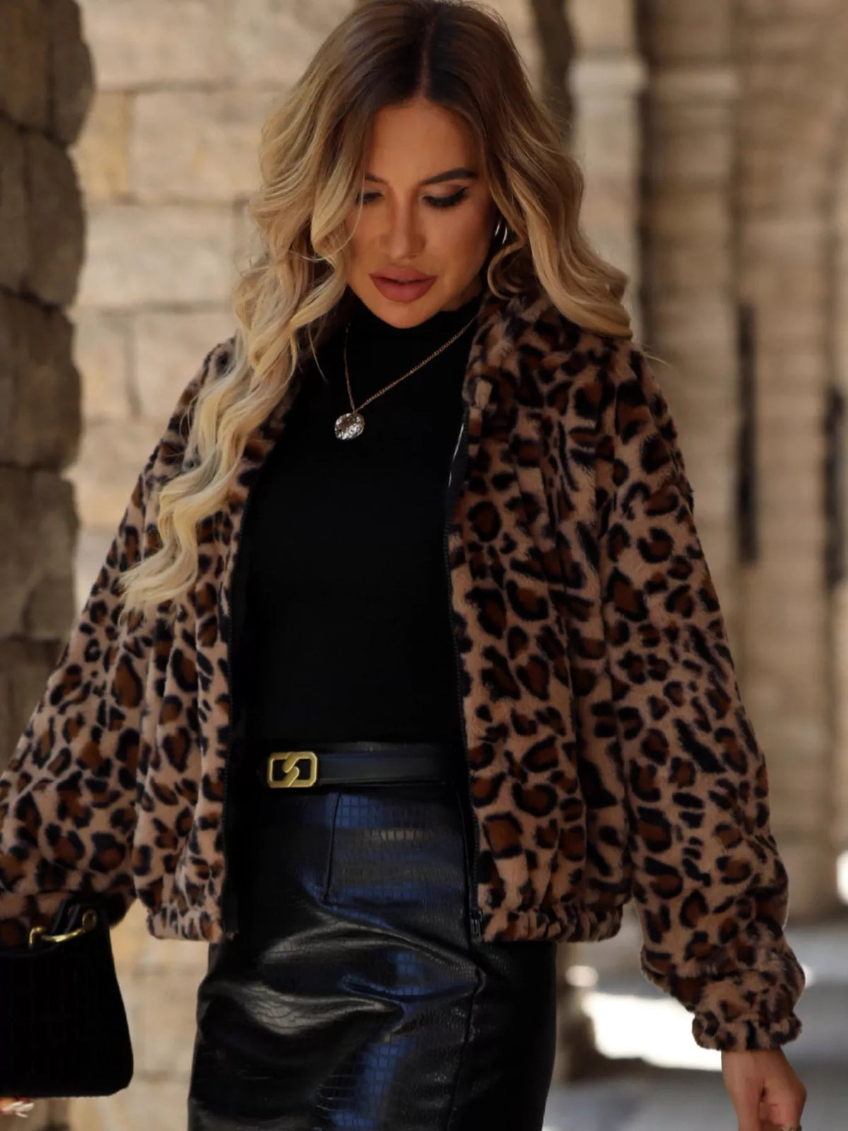 Woman wearing an Evie's Dreamland leopard print faux fur zip-up jacket over a black top and leather skirt.