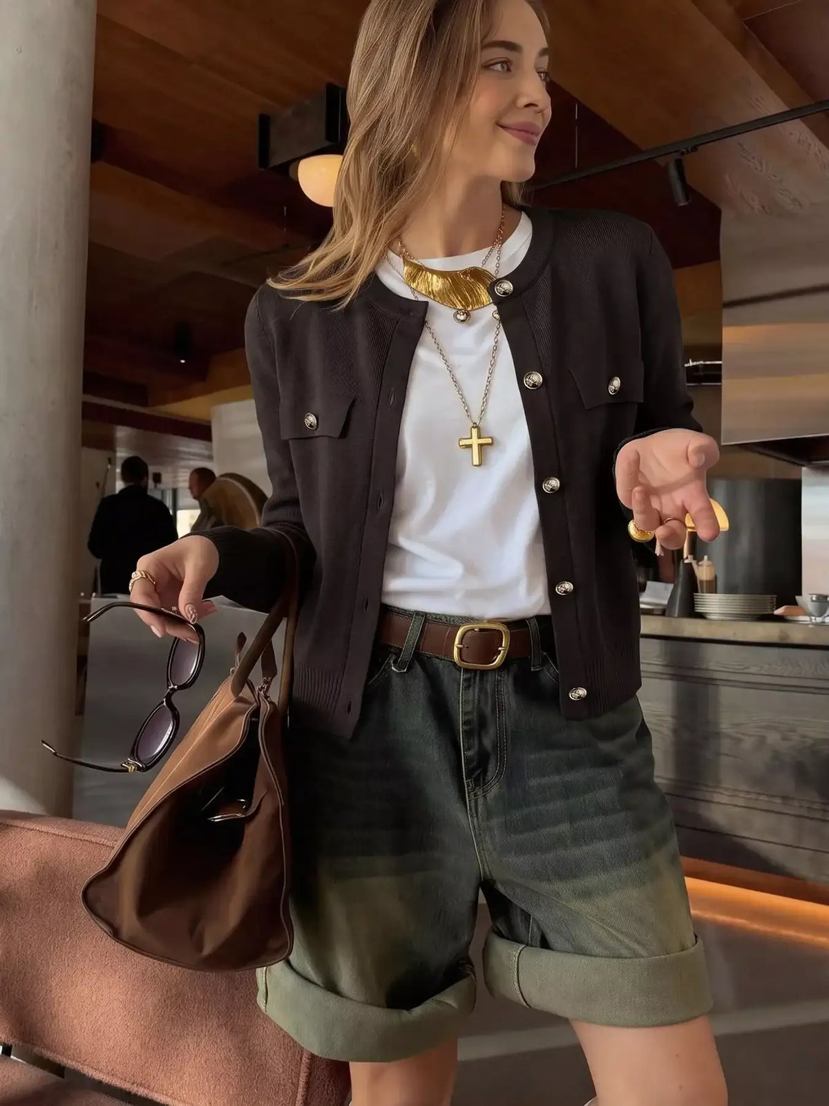 Woman wearing an Evie's Dreamland black button-down cardigan over a white tee and denim shorts.