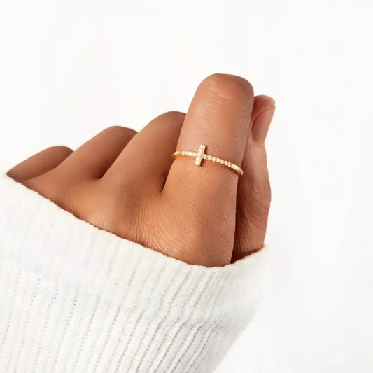 Woman wearing a gold-tone Evie's Dreamland sterling silver cross ring embellished with small crystals.