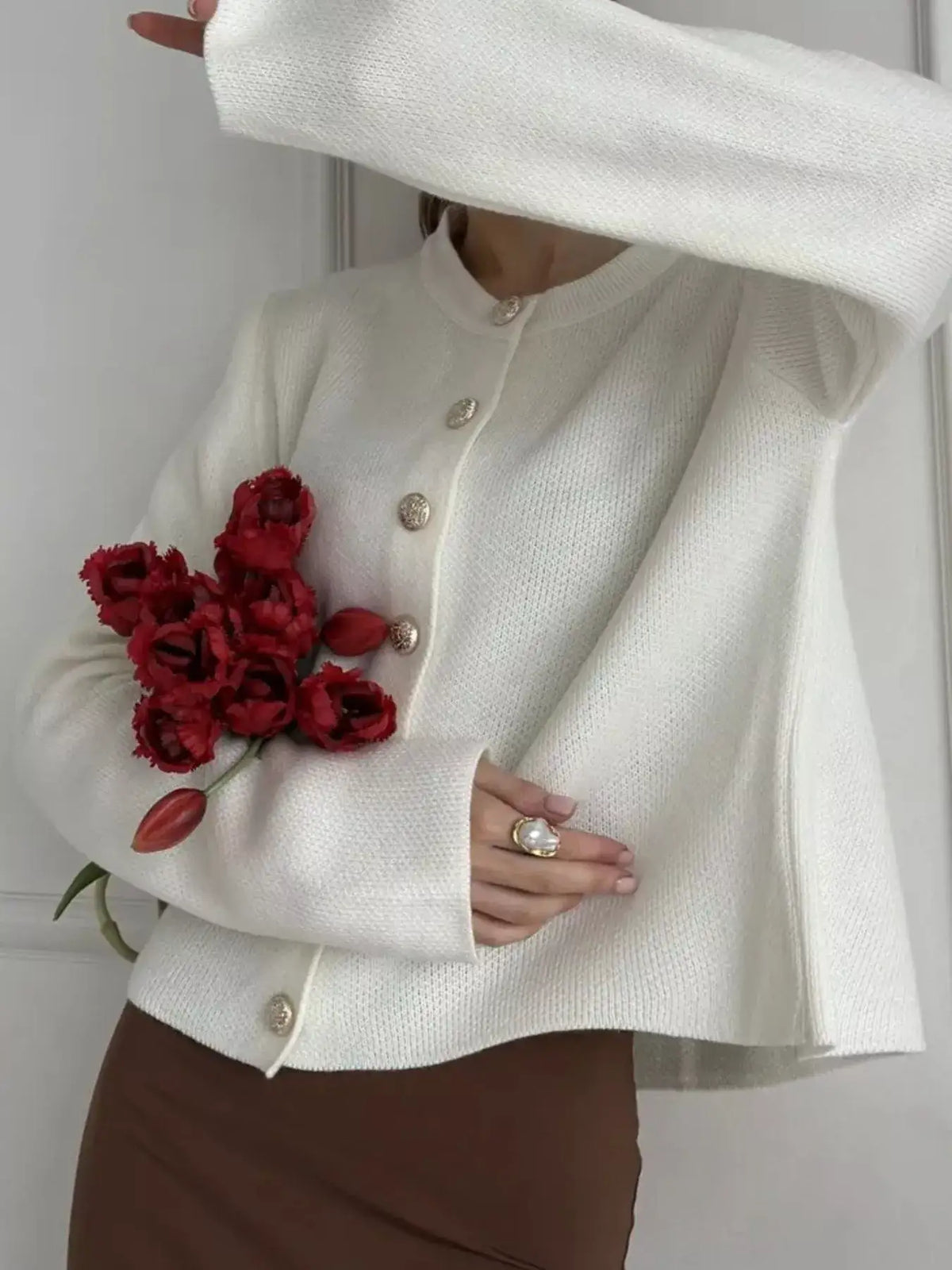 Woman wearing an Evie's Dreamland white crew neck button down cardigan with gold buttons and red tulips.