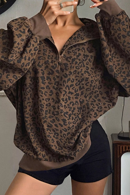 Woman wearing brown leopard print quarter-zip sweatshirt with ribbed texture and black shorts