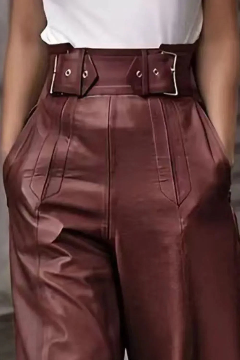 Close-up of woman wearing high-waisted burgundy leather pants with matching belt and white top