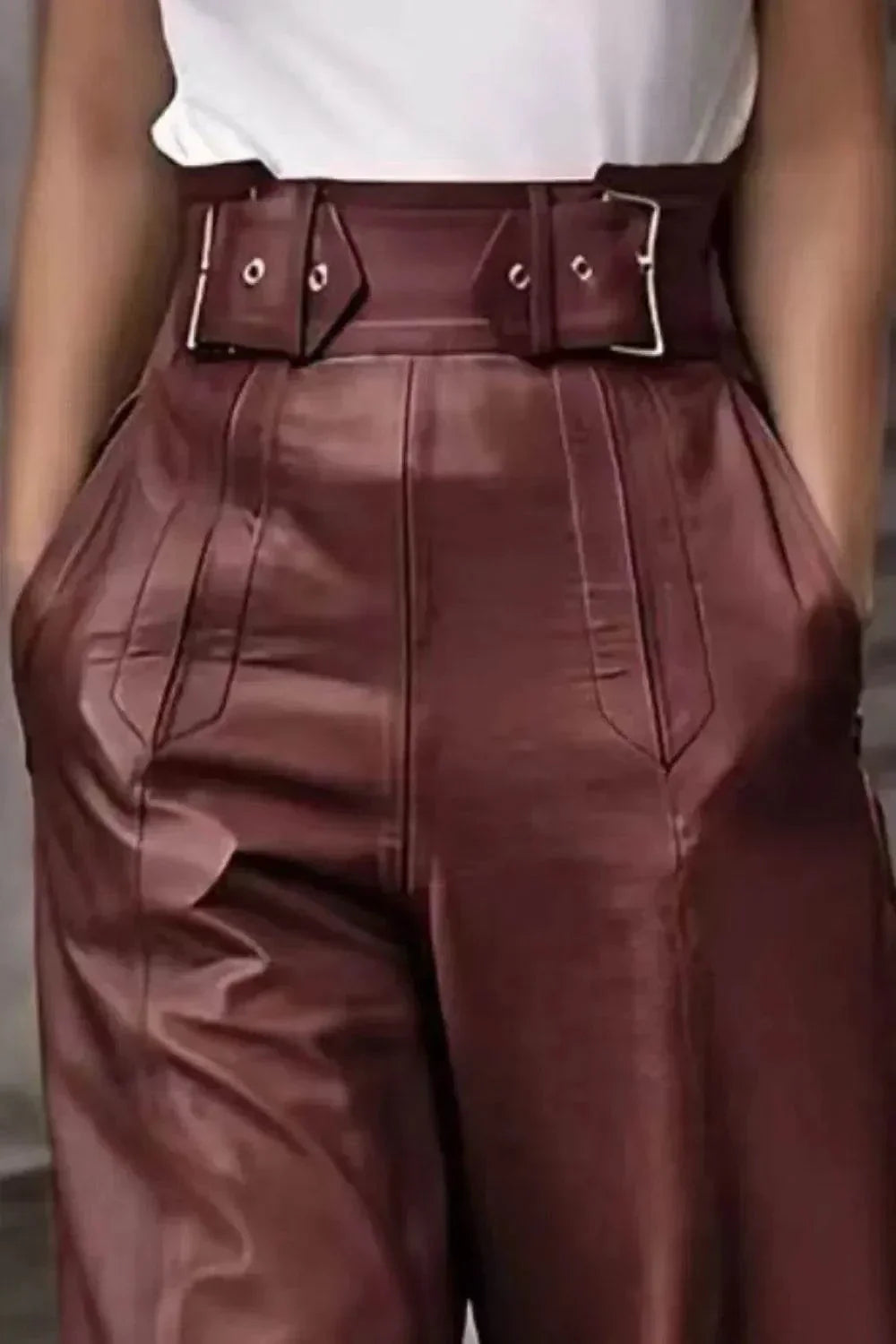 Close-up of woman wearing high-waisted burgundy leather pants with matching belt and white top