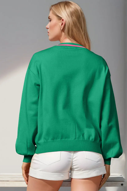 Rear view of woman wearing green long-sleeve sweater and white rolled shorts in bright setting