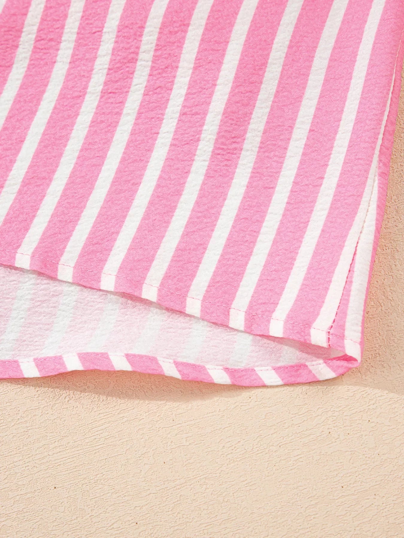 Close-up of pink and white striped fabric on textured beige surface
