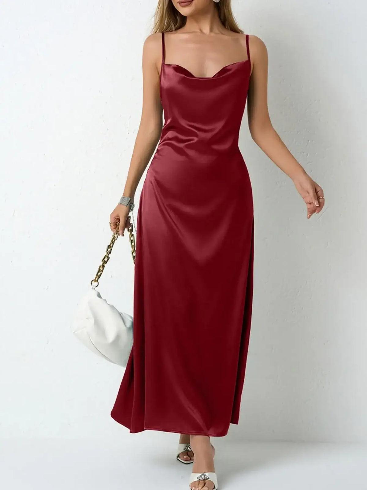 Woman wearing a burgundy satin cowl neck slip maxi dress from Evie's Dreamland with a white handbag.