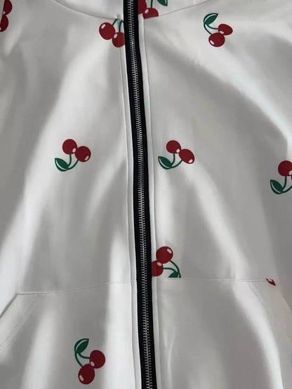 White zip-up hoodie with red cherry prints and green leaves, close-up detail of front zipper