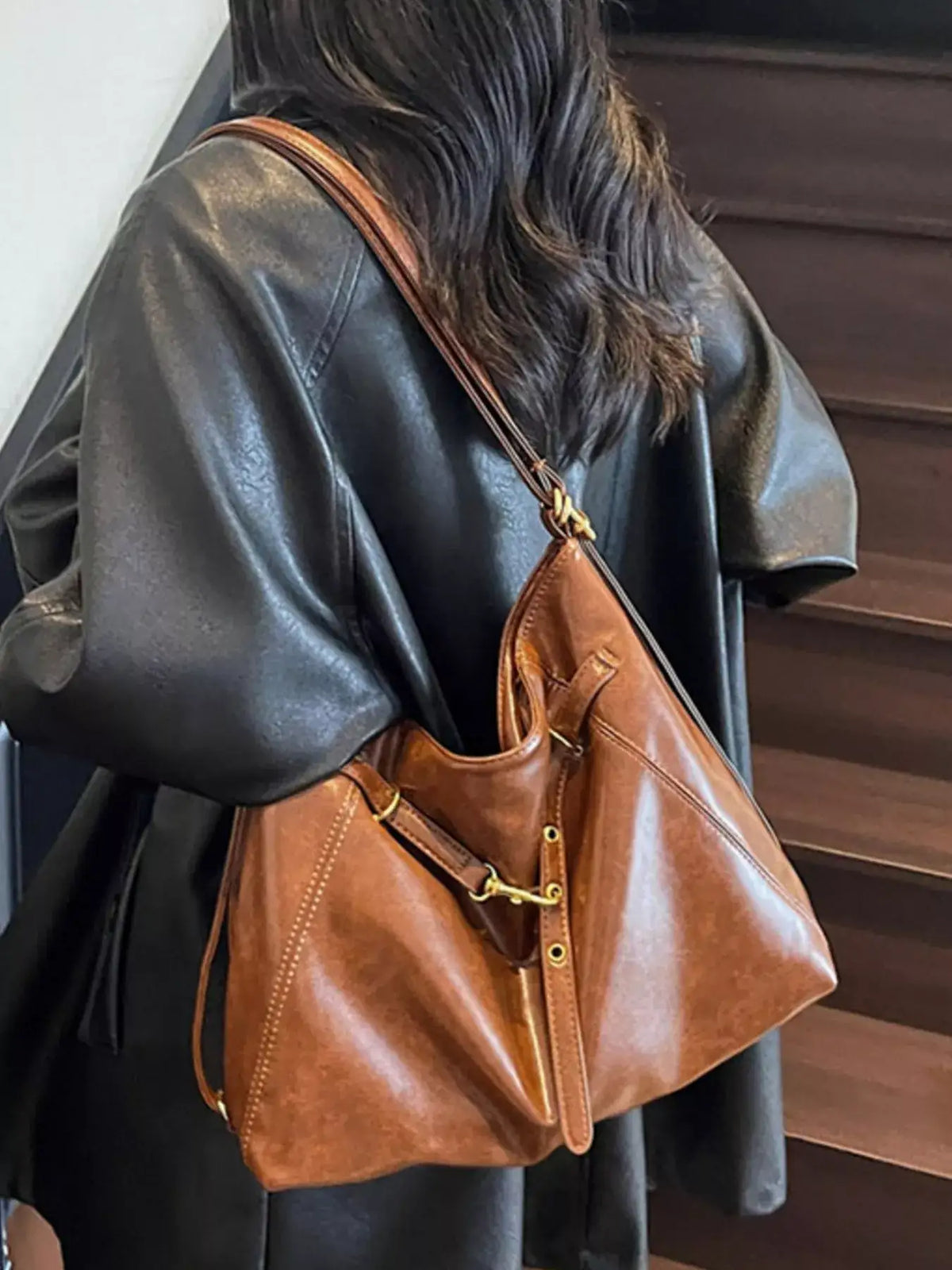 Woman wearing a black leather jacket and a brown Evie's Dreamland vintage style PU leather shoulder bag.