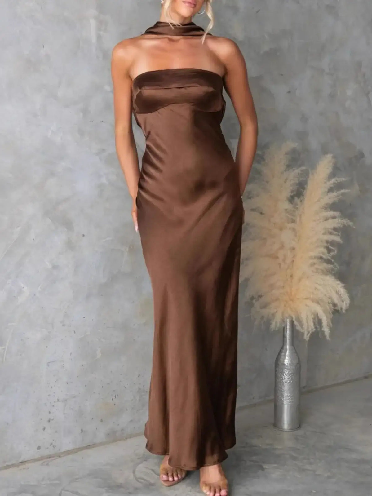 Woman wearing a brown satin tube maxi dress by Evie's Dreamland with a strapless neckline and slim fit.
