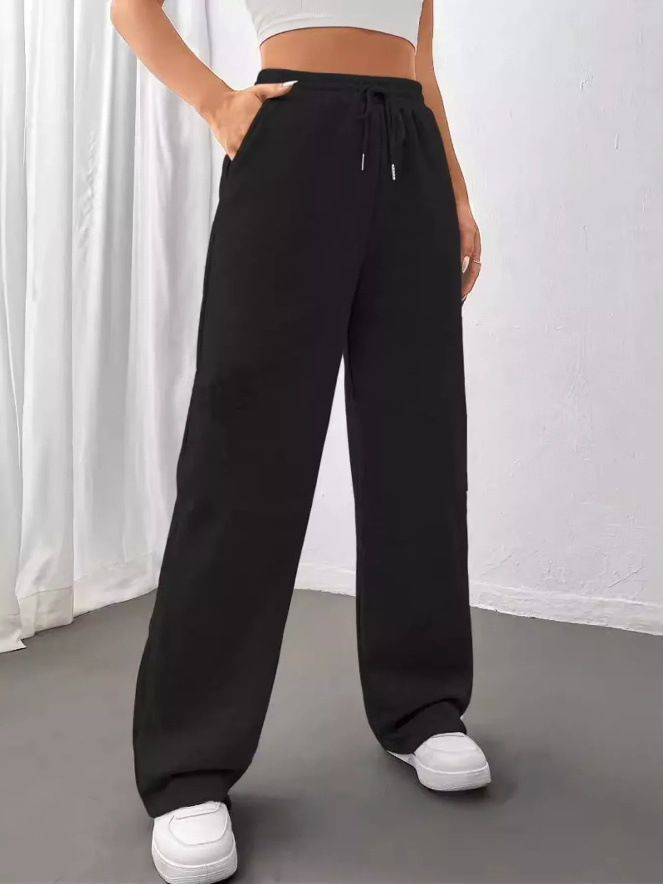 Woman wearing black wide-leg casual pants with drawstring and white sneakers