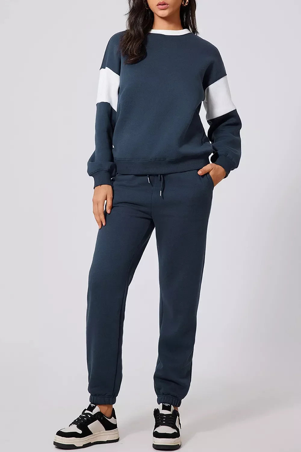 Woman wearing navy blue and white color block sweatshirt and matching jogger pants with black and white sneakers