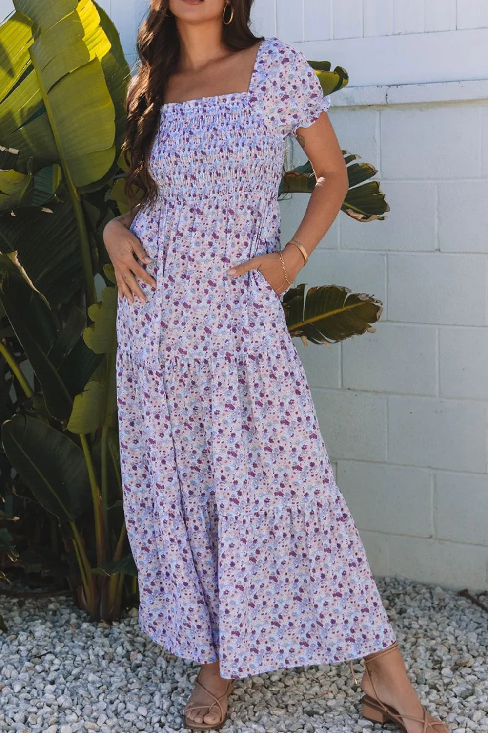Woman wearing a floral print maxi dress with short sleeves and pockets, standing outdoors.