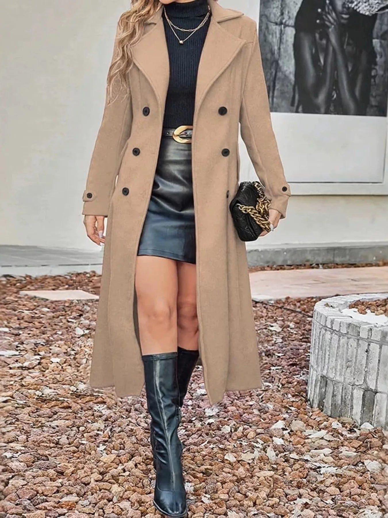 Woman wearing a long tan trench coat, black leather mini skirt, and knee-high black boots.