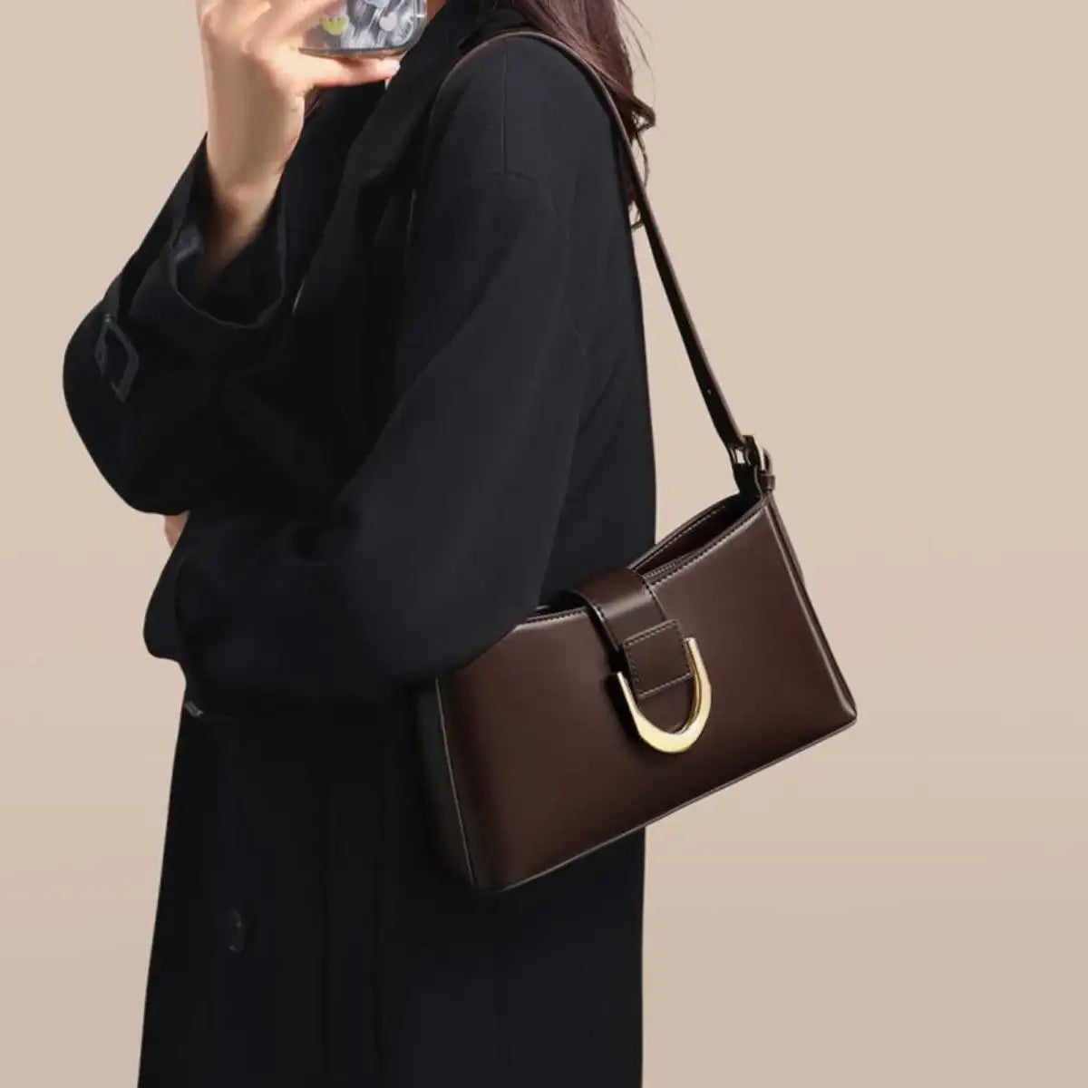 Woman in a black coat carrying a brown PU leather shoulder bag with a gold ring detail by Evie's Dreamland.