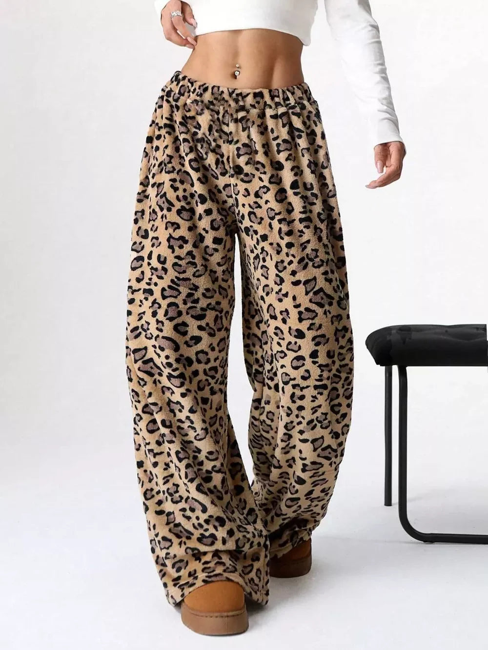 Woman wearing cozy leopard print fleece pants paired with brown shoes and white cropped long-sleeve top