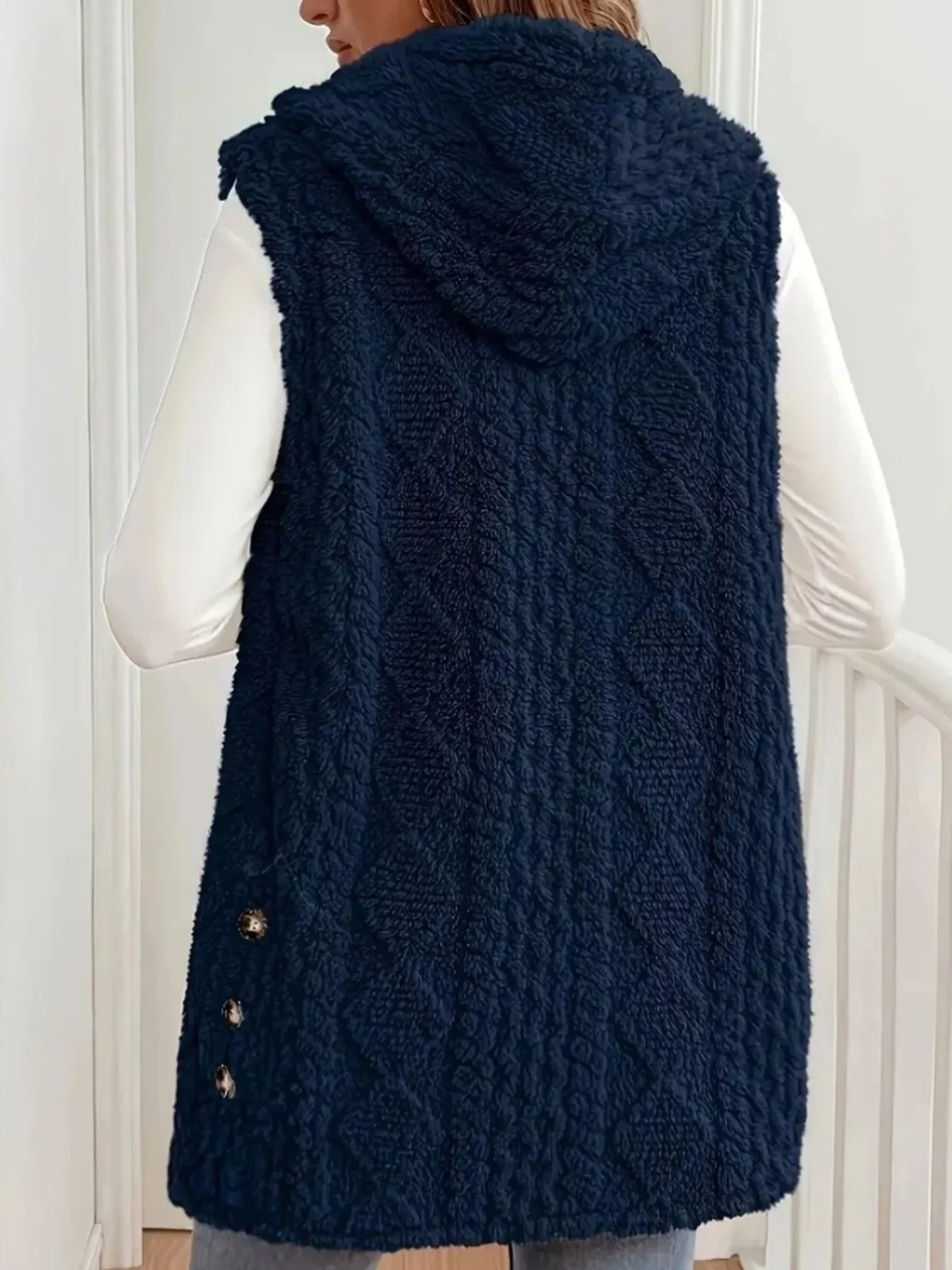 Back view of a woman wearing a navy blue textured sherpa fleece vest with hood and button details