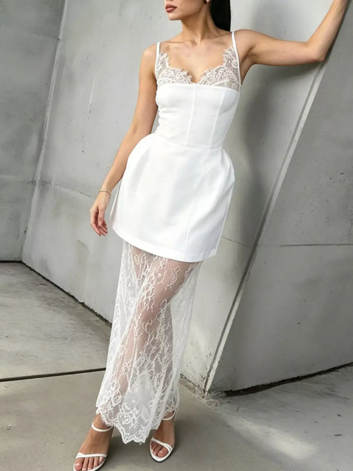 White Evie's Dreamland lace corset mini dress with a sheer lace overlay skirt and white heels.