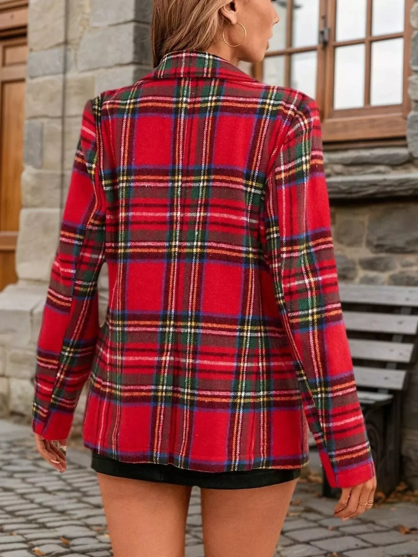 Back view of a woman wearing a red plaid oversized blazer and black skirt.