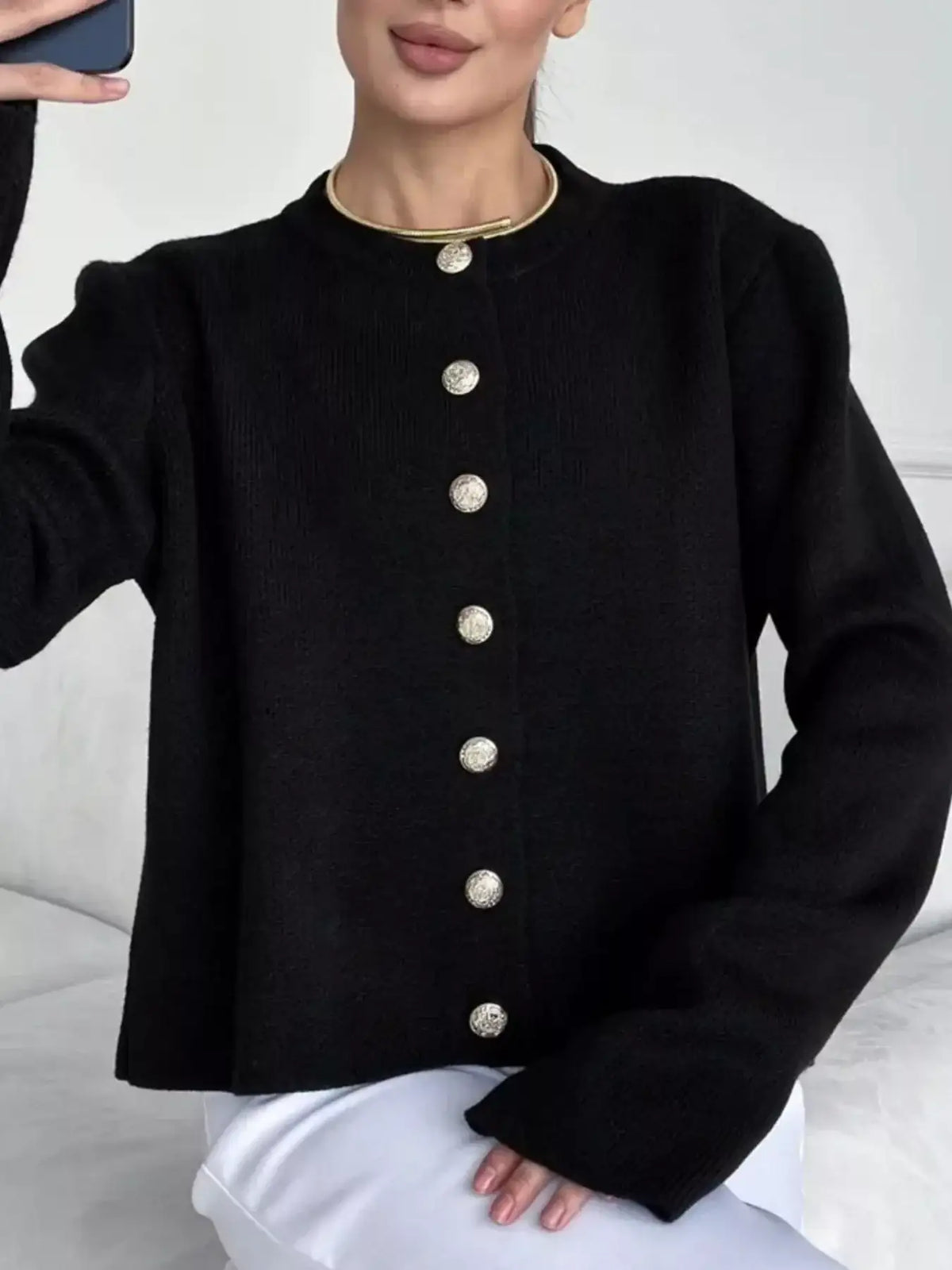 Woman wearing a black crew neck button down cardigan by Evie's Dreamland with gold buttons.